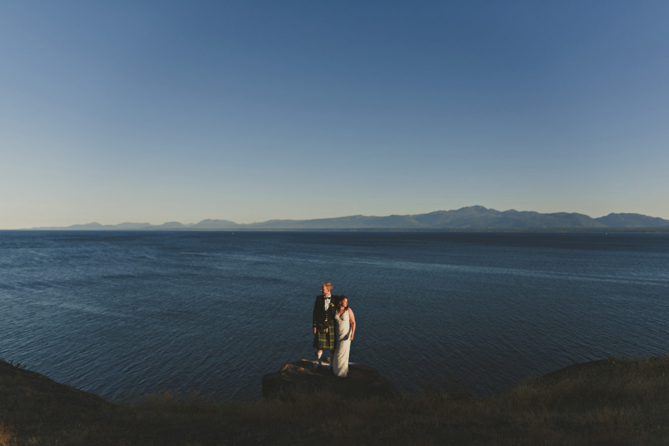 bride and groom on a rocky outcropping on a cliff overlooking the ocean