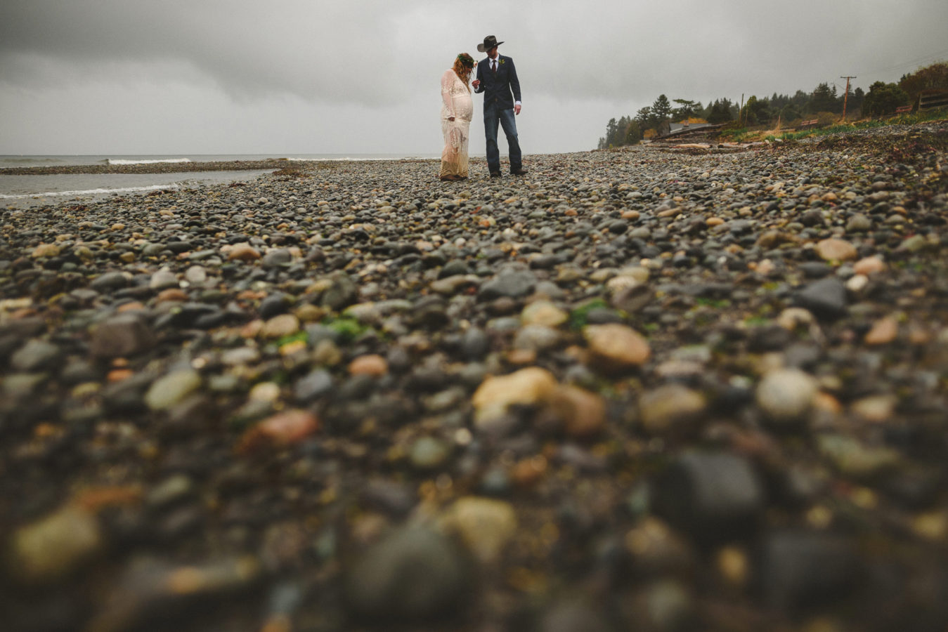 looking along a rocky beach at a bride and groom on their wedding day